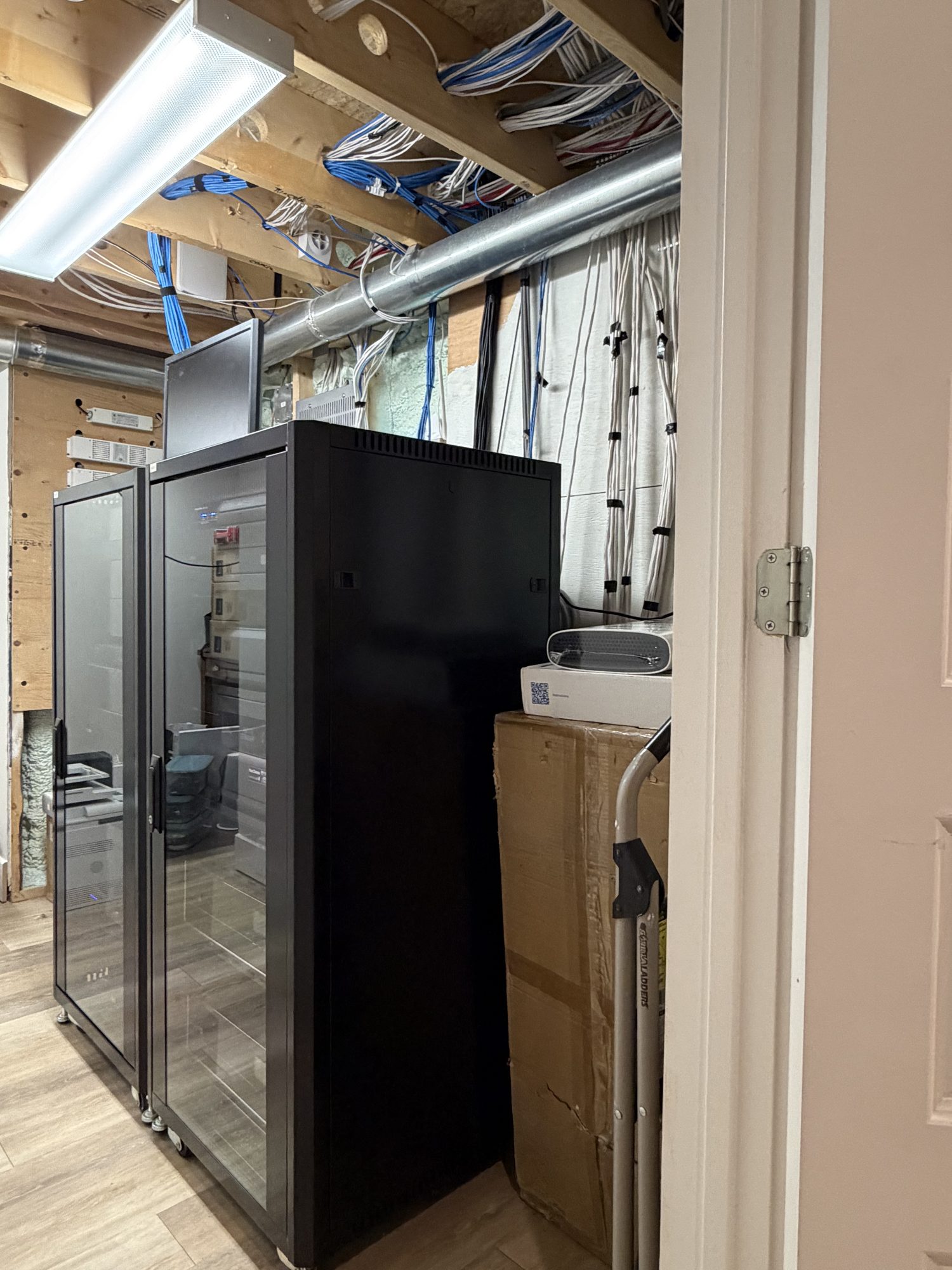 Two black glass-door equipment racks with structured cabling overhead