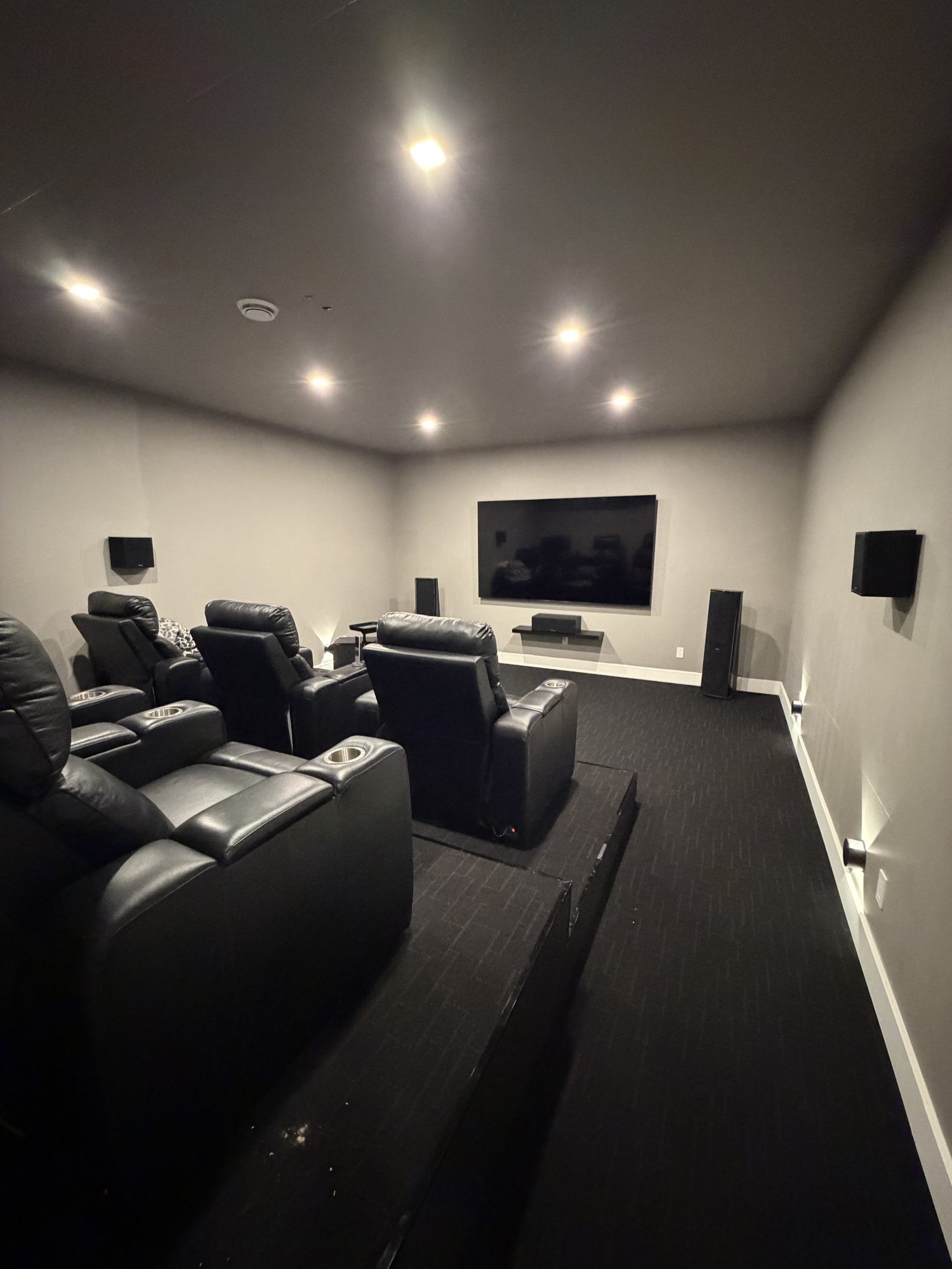 Dedicated home theatre with tiered leather recliners and surround speakers
