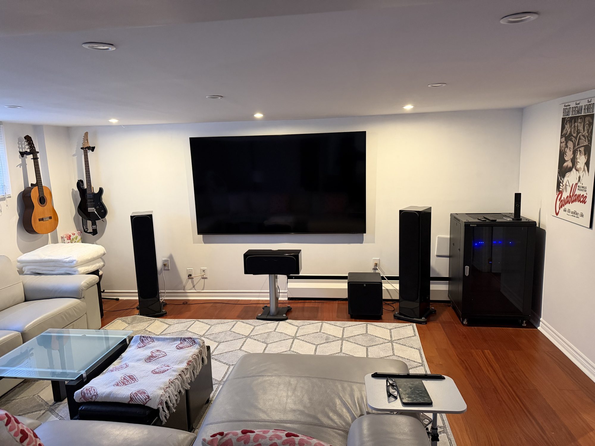 Home theatre media room with wall-mounted TV, tower speakers and equipment rack